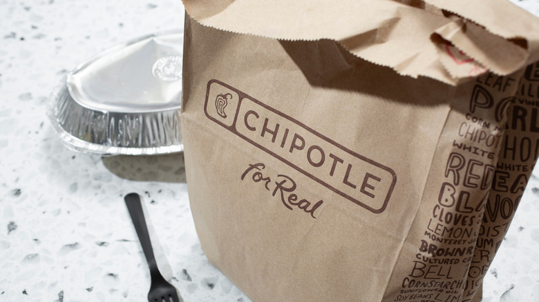 A brown paper Chipotle bag and takeout container