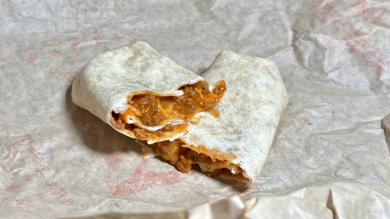 A Chili Cheese Burrito split in half on top of its wrapper