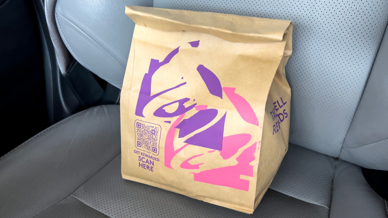 A bag of Taco Bell food sitting on the seat of a car