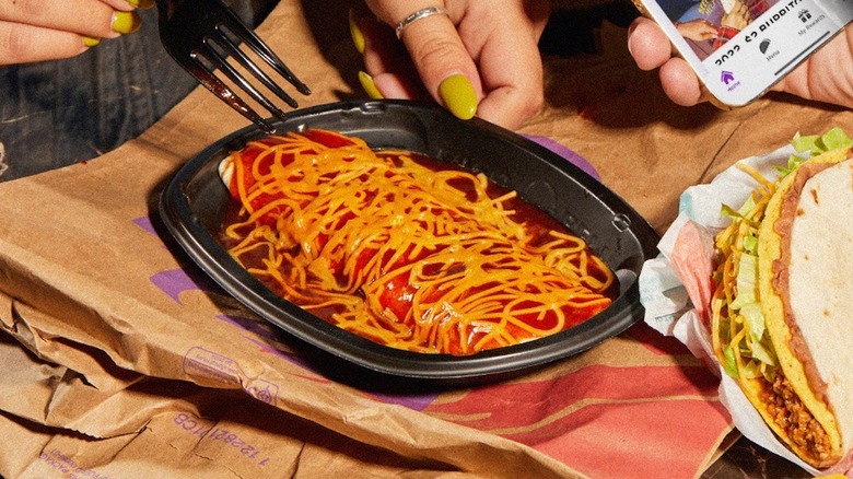 Fork digging into to-go container with Taco Bell Enchirito
