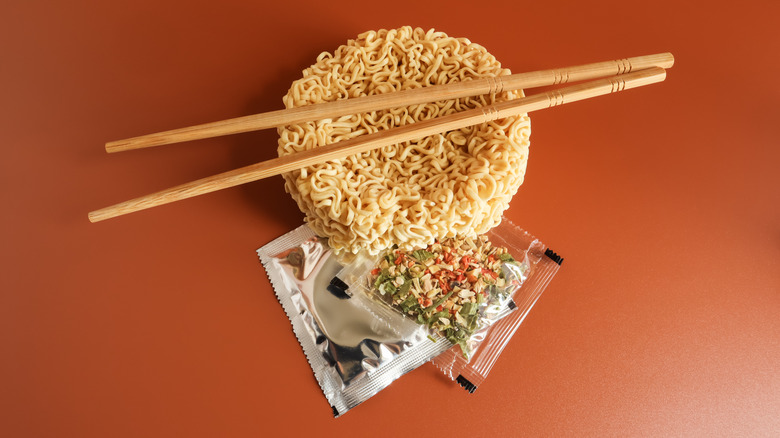 Raw instant noodles with chopsticks and seasoning and dried vegetable packets.