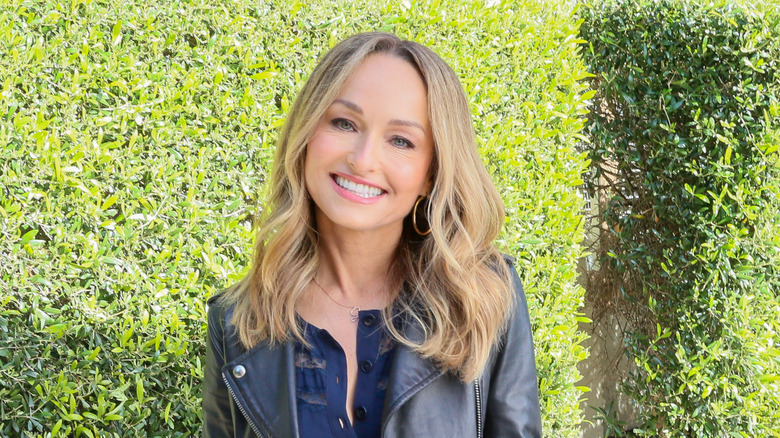 Giada De Laurentiis smiling in front of green bushes outside