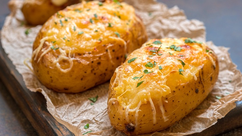 Two baked potatoes with cheese and parsley