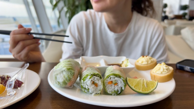 Person eating spring rolls in airport lounge