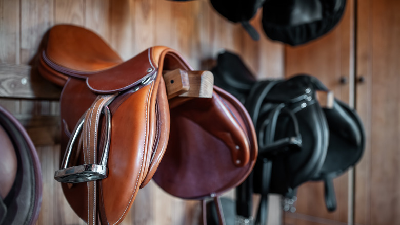 Brown and black saddle hanging on wooden wall