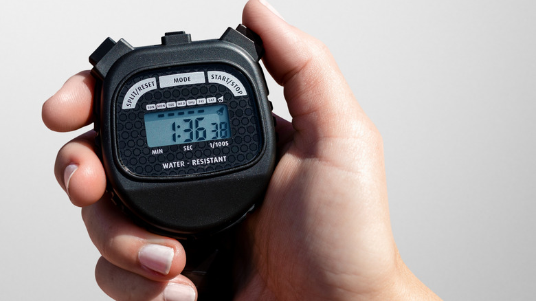 Hand holding a black stop watch