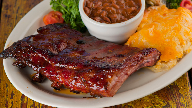 A plate of BBQ ribs with baked beans on the side.