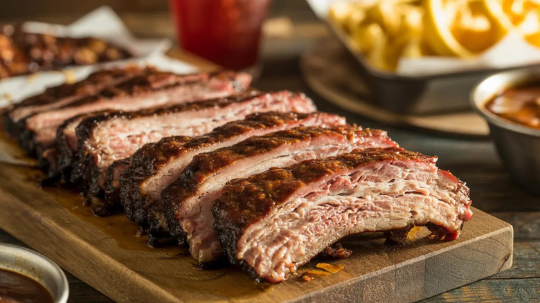 Sliced barbecue ribs on a wooden cutting board.