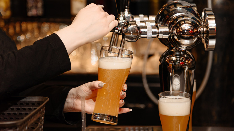 A bartender pouring beer into a glass.
