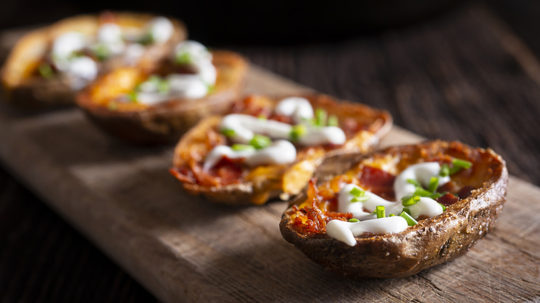 A line of perfectly cooked potato skins on a wooden board