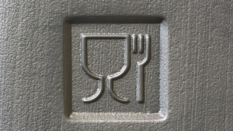 A food safe symbol with fork and glass pressed into what appears to be Styrofoam.