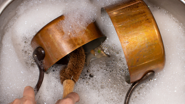 Washing copper pots in soapy water
