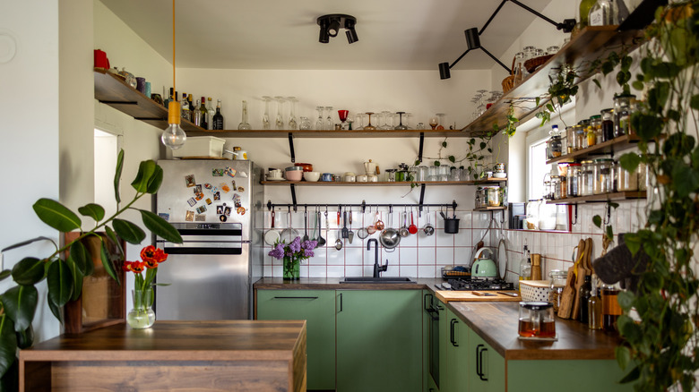 An organized but cluttered kitchen with open shelves and green cabinets
