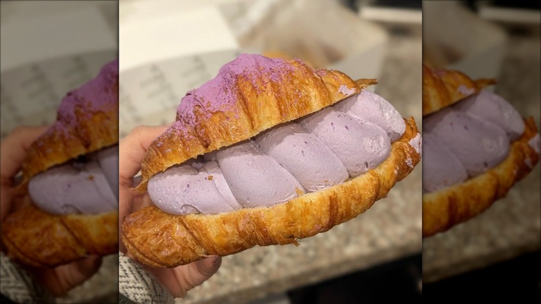 Hand holding Ube Halaya Croissant with bright purple cream from Cafe Mochiko