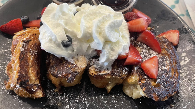 La Panaderia tequila french toast with berries and whipped cream on a black plate