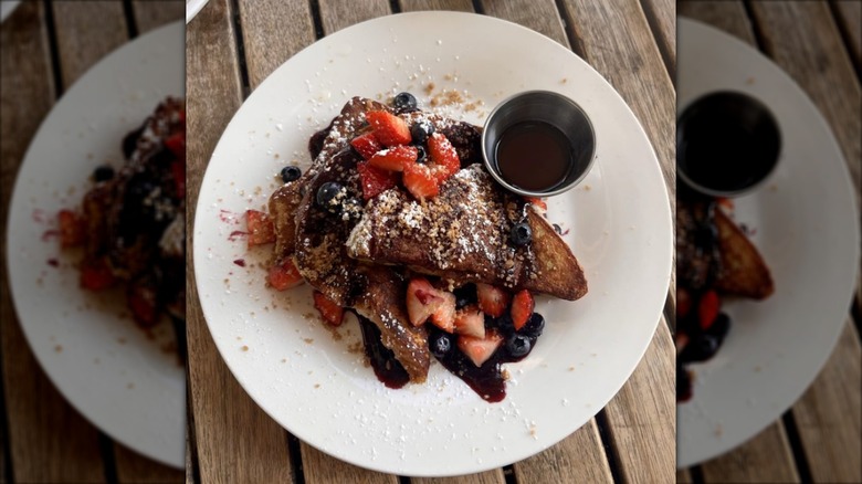Nutmeg Bakery's stuffed French toast with berries and a side of syrup on a white plate