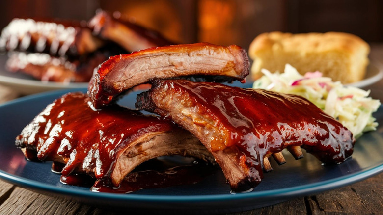 A plate of pork ribs with barbecue sauce and sides