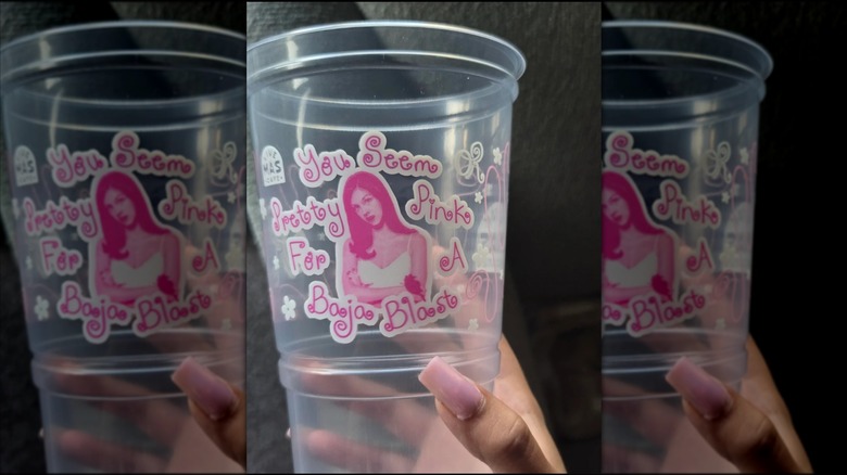 Hand holding an Olivia Rodrigo-themed Taco Bell drink cup