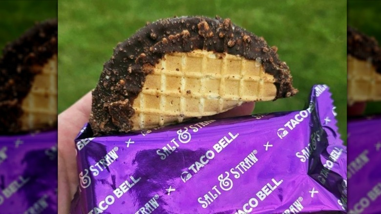 A hand holding the packaging of a Taco Bell Churro Ice Cream Taco, mirrored