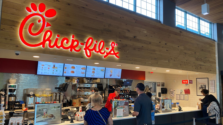 Customers standing and looking at Chick-fil-A's menu.