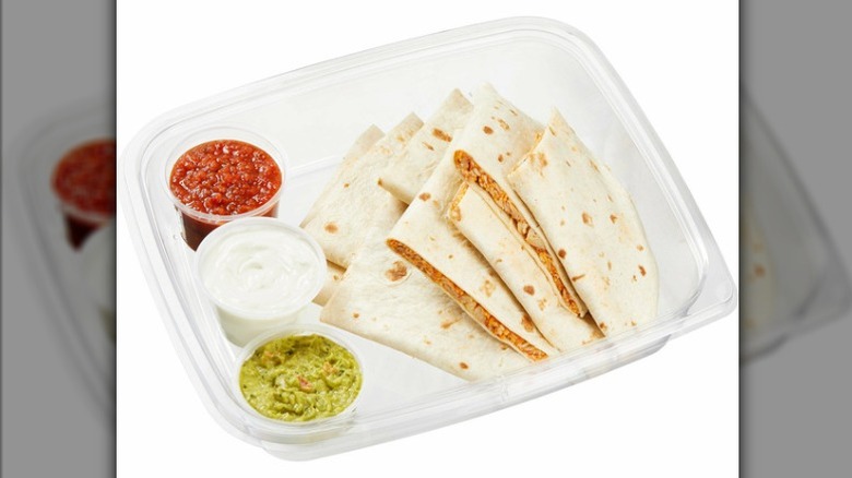 The Kirkland Signature Chicken Quesadilla from Costco in plastic tray with salsa, sour cream, and guacamole on side