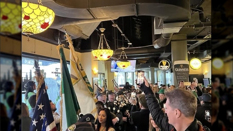 Crowded bar with people celebrating St. Patrick's Day at Lizzie McNeill's in Chicago, with flags and men playing bagpipes