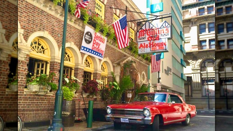 Exterior of McGillin's Olde Ale House in Philadelphia with vintage car parked outside brick building with U.S. flag