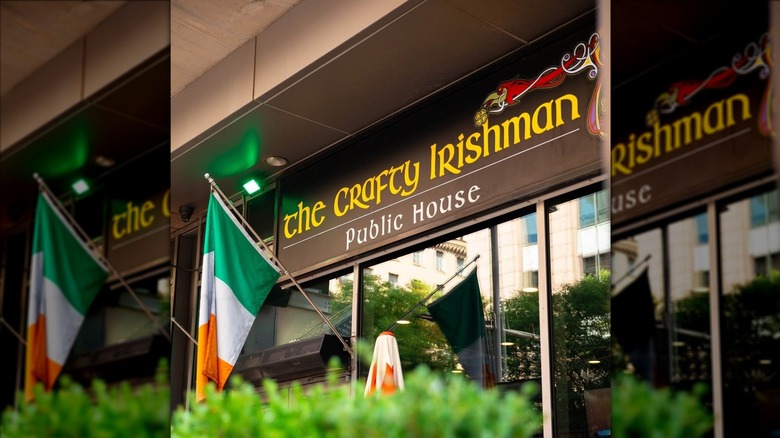 Exterior of The Crafty Irishman pub in Dallas with Irish flag hanging beneath bar sign