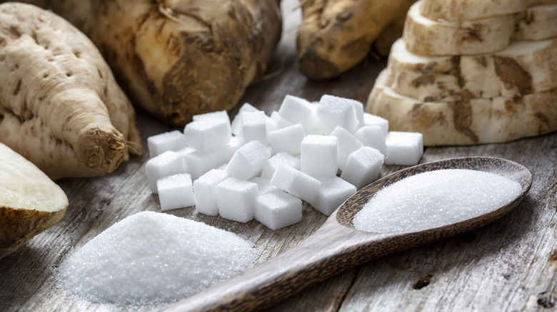 Raw beet sugar cubes on a wood table next to sugar beets