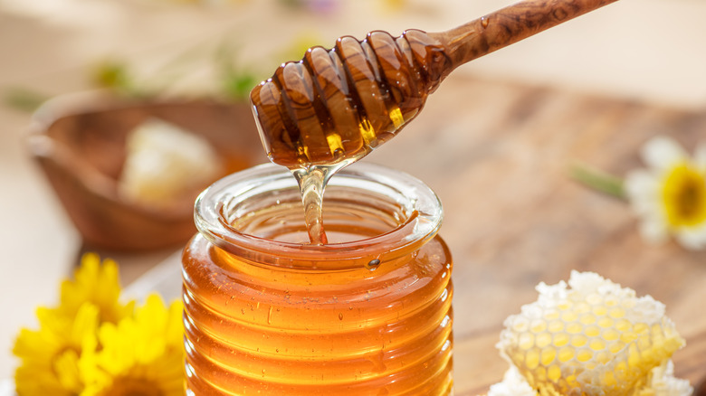 Honey in a glass jar with a wooden honey dipper