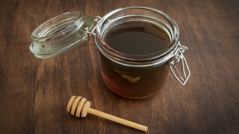 A glass jar of sorghum syrup on a wood table