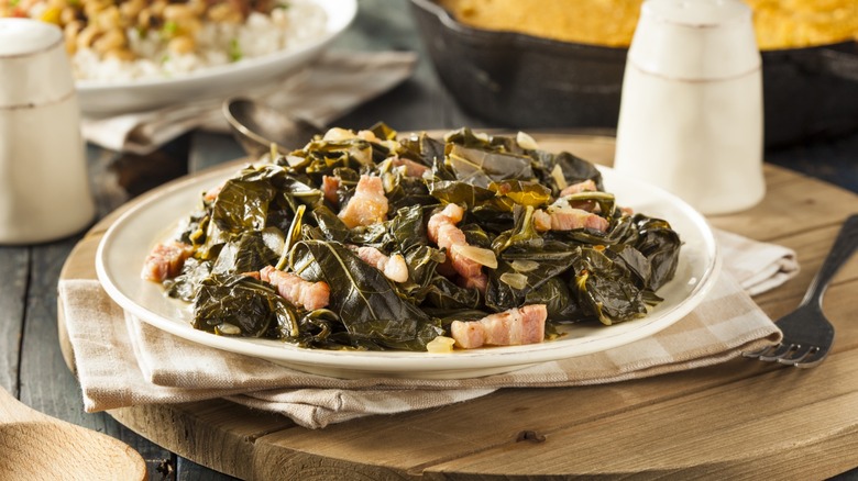 Southern Style Collard Greens with Salt Pork on plate on wooden surface with cloth napkin and fork