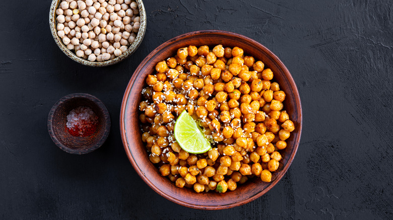 Overhead shot of a bowl of crispy chickpeas with spices and a wedge of lime
