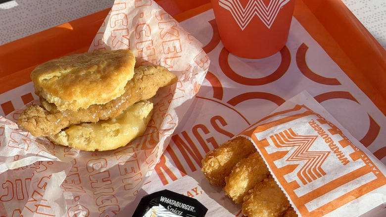 A tray of Whataburger featuring the honey butter biscuit sitting on its wrapper with a side of hash brown Krispers