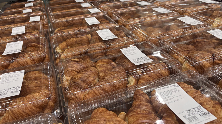 a shelf stacked with clear clamshells holding costco butter croissants