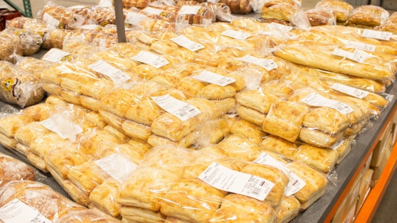 a shelf stacked with bags of Costco Kirkland Signature ciabatta rolls