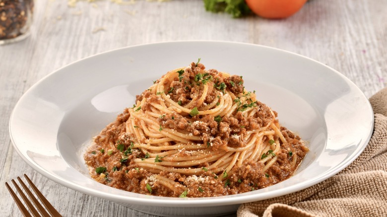 SPAGHETTI BOLOGNESE with fork served in dish isolated on wooden table side view of italian fast food