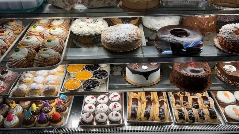 Display case filled with baked goods, including cakes, cupcakes, eclairs, and more at Holtermann's Bakery in Staten Island, New York