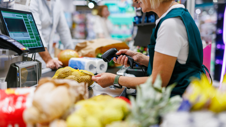 A grocery store cashier scanning a sack of potatoes at the checkout