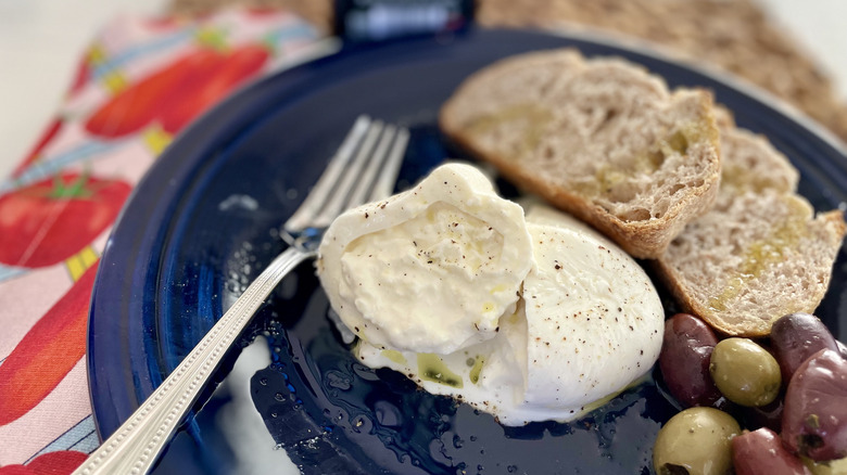 Aldi burrata ball sliced in half and served olives and bread
