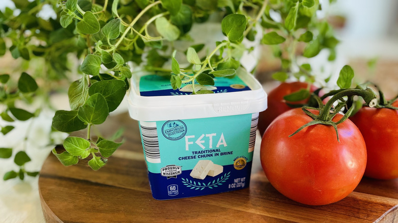 A container of Aldi feta cheese with tomatoes and fresh oregano