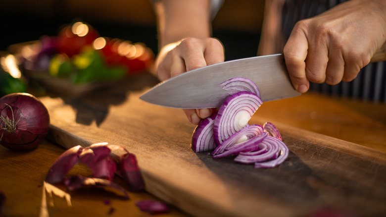 hands chopping a red onion