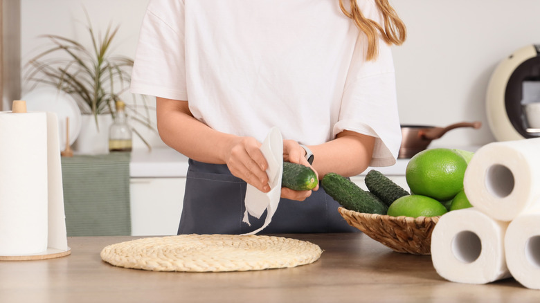 hands holding cucumber and paper towel