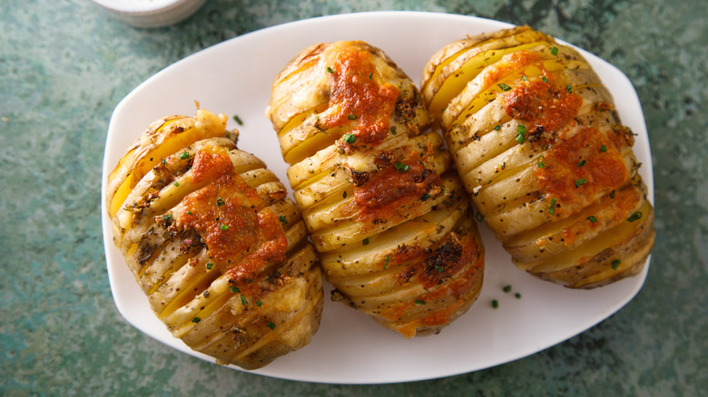 three hasselback potatoes on a white plate