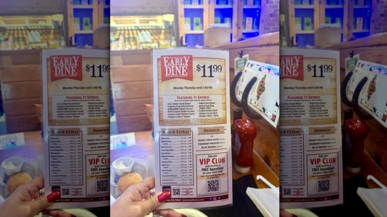 A customer holding the Early Dine menu from Texas Roadhouse.