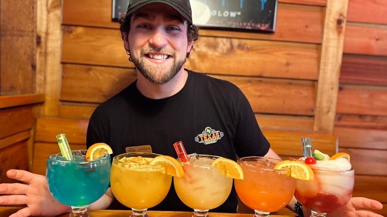 Different flavors of Texas Roadhouse's margaritas in a line on a table.