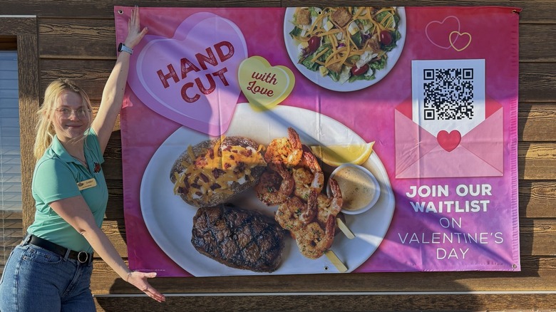 A Texas Roadhouse employee presenting a sign about Valentine's Day.