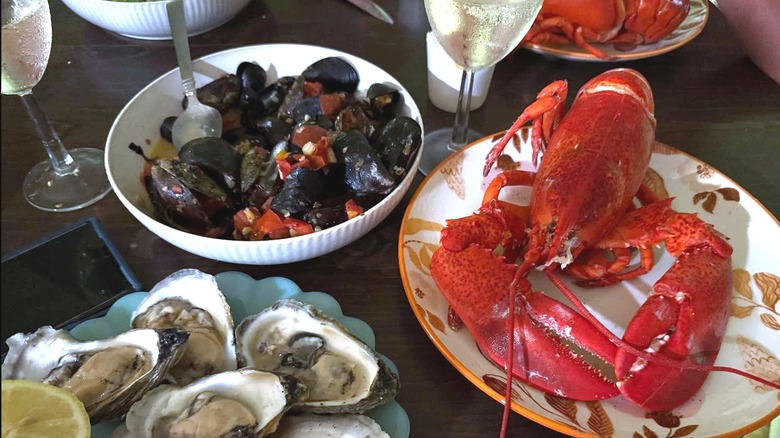 Various dishes including scallops, oysters, and lobster with glasses of white wine at Il Forno di Tutti