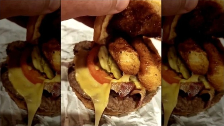 A hand opening a big mozz sandwich to show the contents