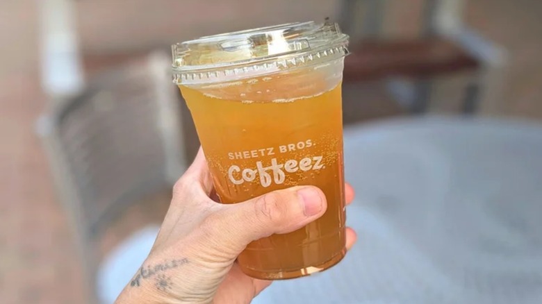 A hand holding a Sheetz peach mango refresher